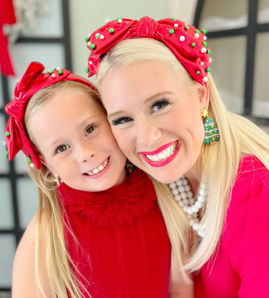The Canton Christmas Shop Child Size Red Christmas Bow Headband with Green and Pearl White Beads by Brianna Cannon on model for holiday parties and family time